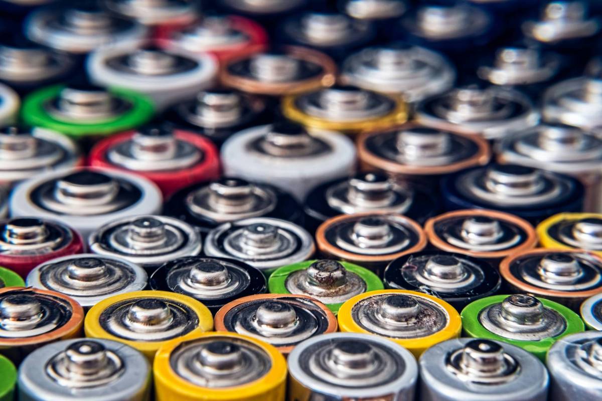 A close-up of assorted colorful battery tops, including green, red, yellow, and silver, closely packed together.