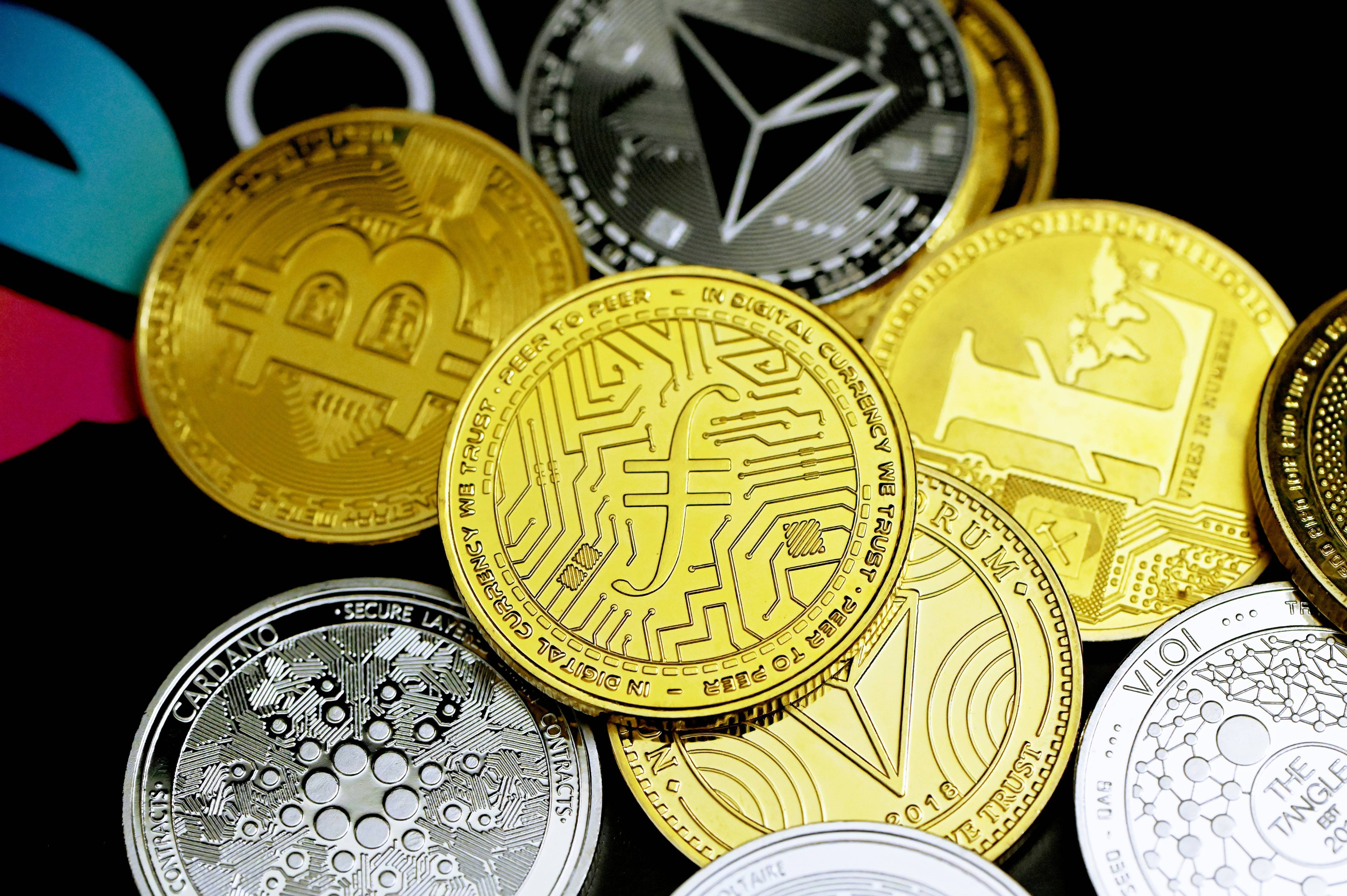 A collection of various gold and silver cryptocurrency coins displayed on a dark background.