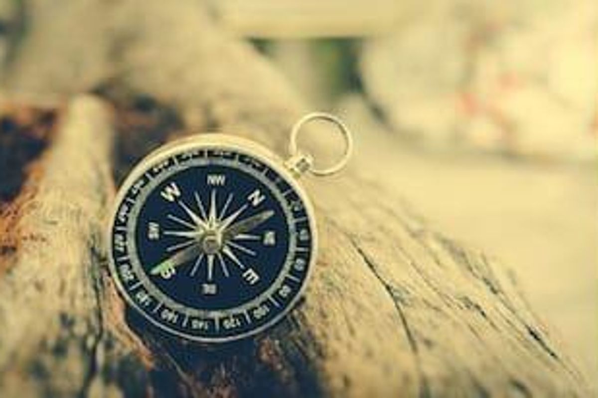 A compass on a log, with a blurred background and warm lighting.