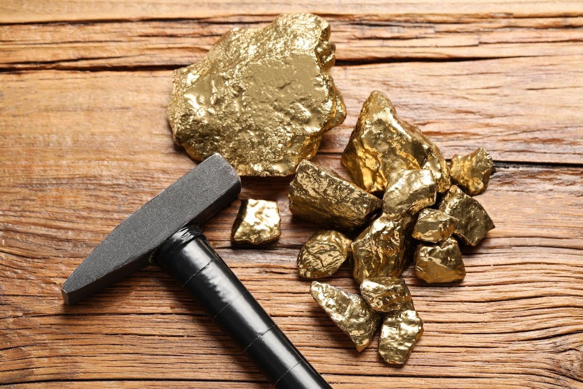 A dozen pieces of gold beside a small hammer. 