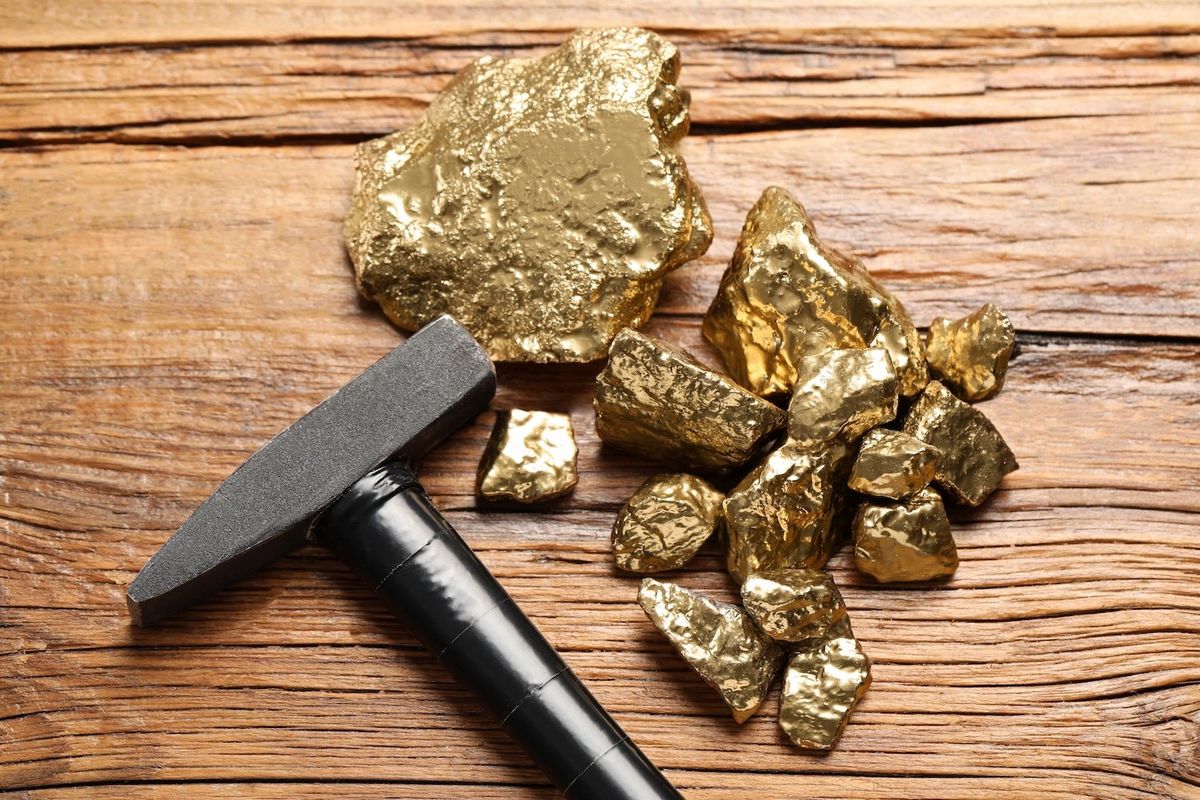 A dozen pieces of gold beside a small hammer.