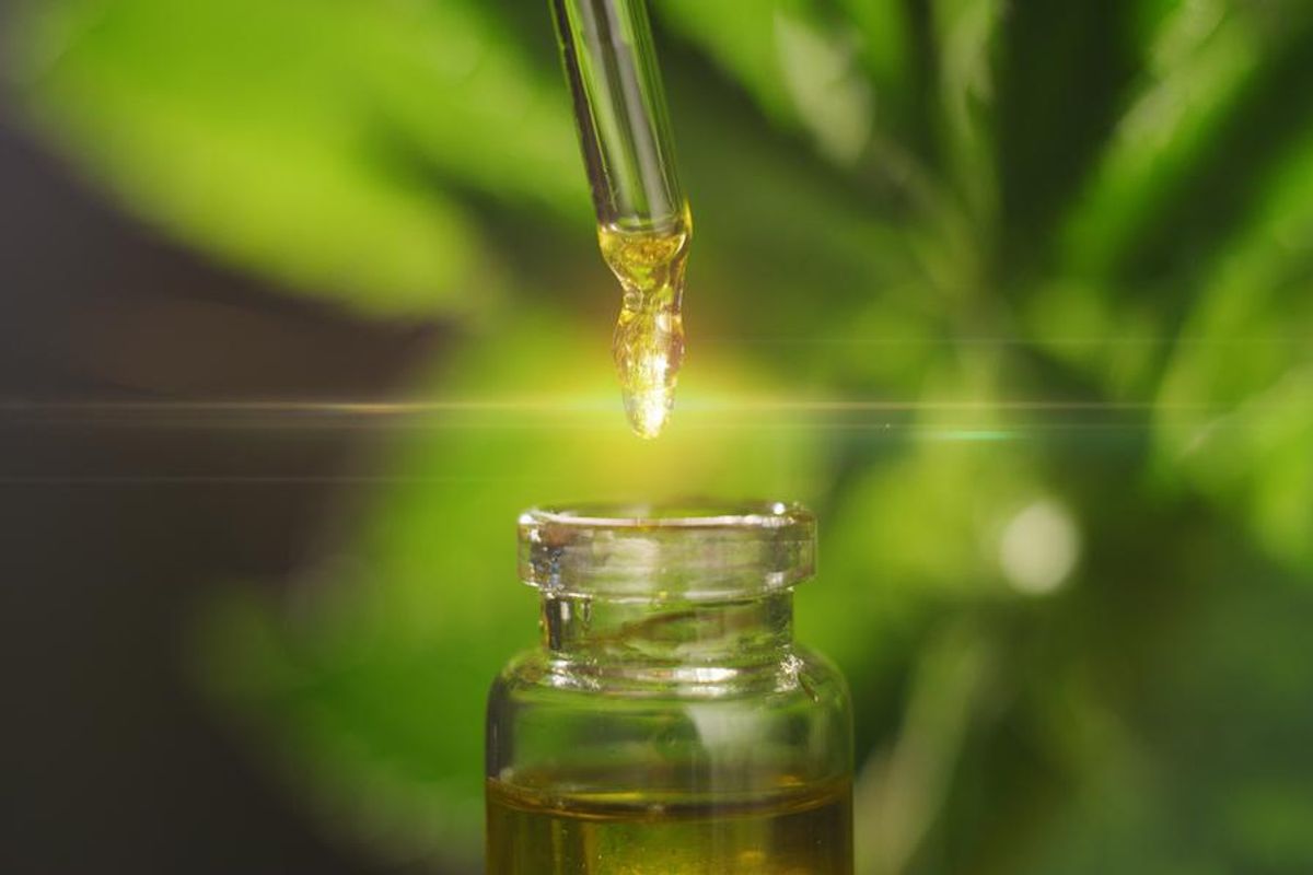 a dropper is withdrawing cannabis extract from a small glass container