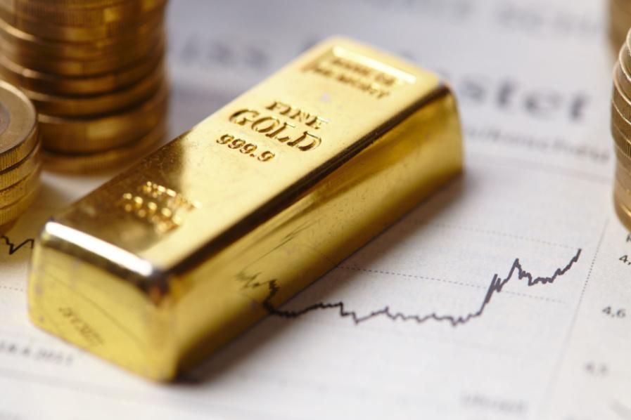 a gold bar and gold coins on top of a stock chart