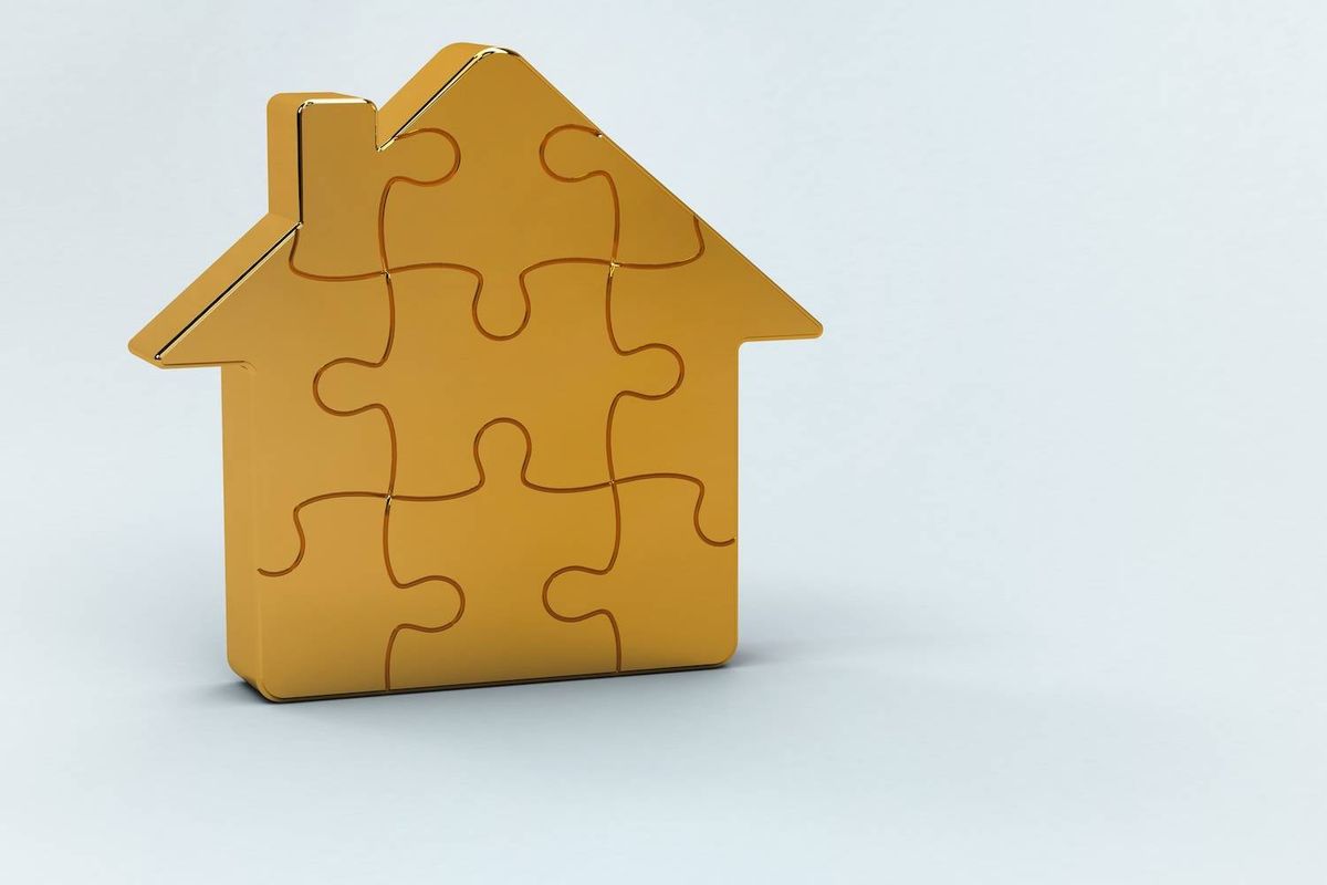 A gold house-shaped puzzle piece stands on a plain light gray background.