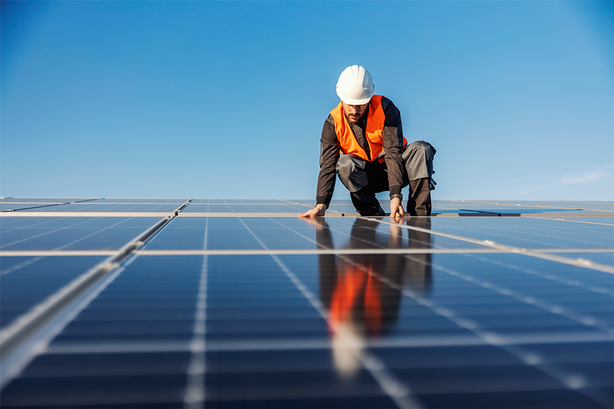 A handyman installing solar panels on a rooftop.