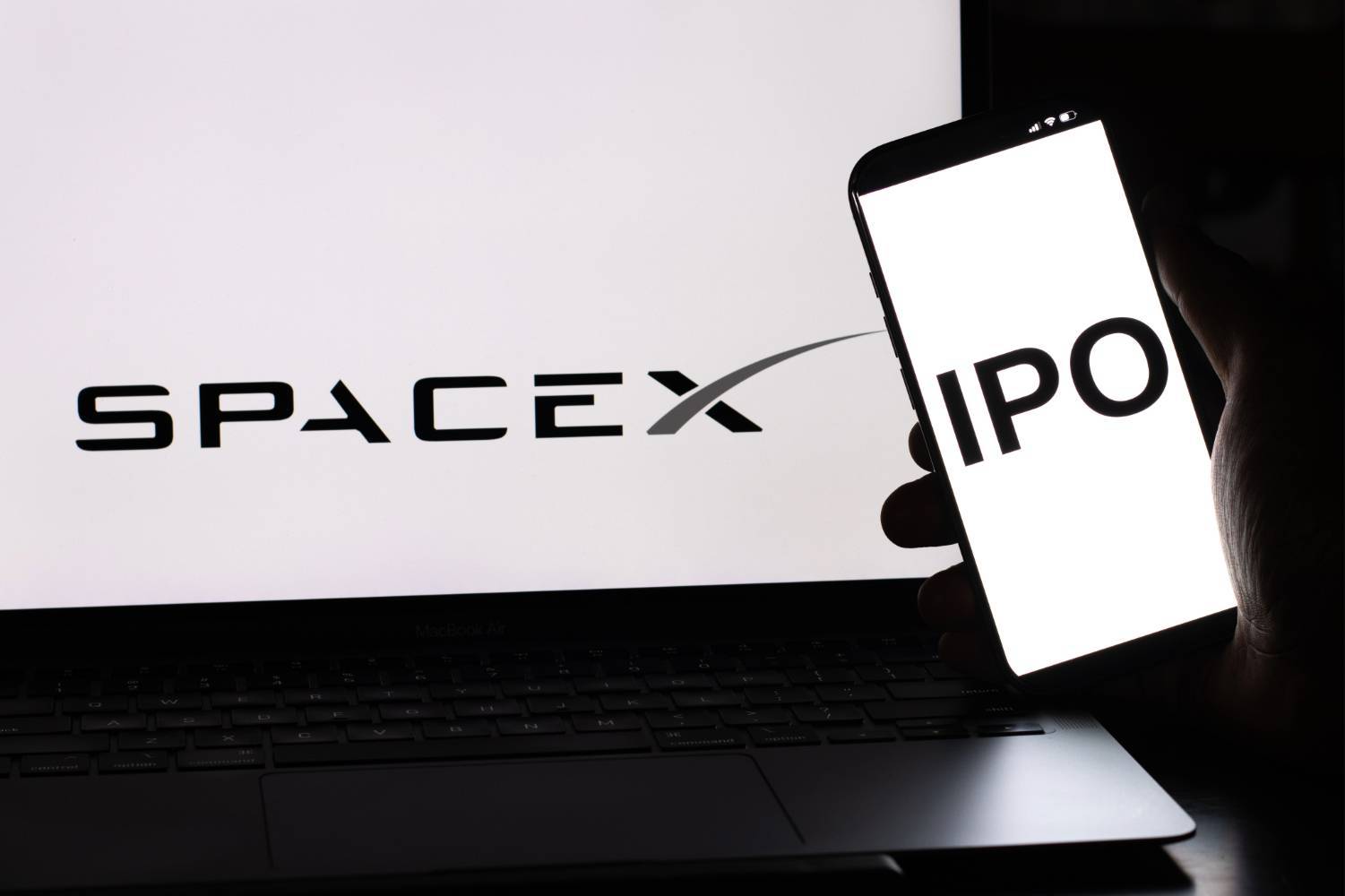 A laptop displays "SpaceX" while a phone shows "IPO."