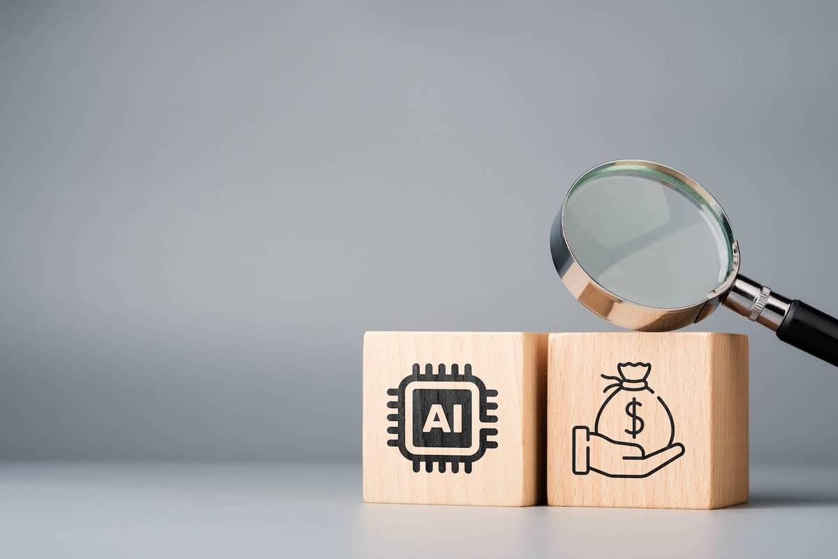 A magnifying glass hovers over wooden blocks with AI and money bag symbols on a gray background.