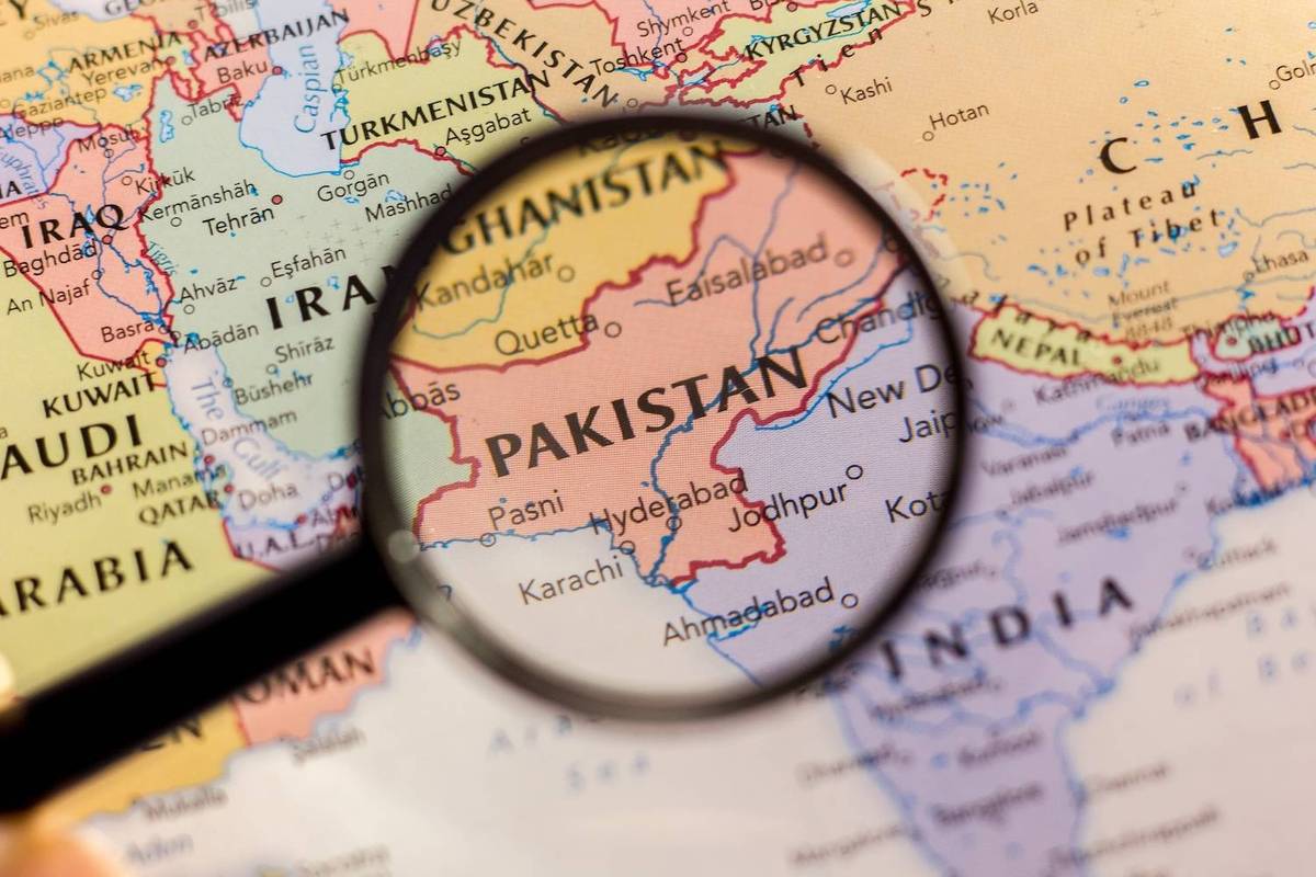 A magnifying glass over a map highlights Pakistan, showing neighboring countries in beige, yellow, and red; text reads: Pakistan.
