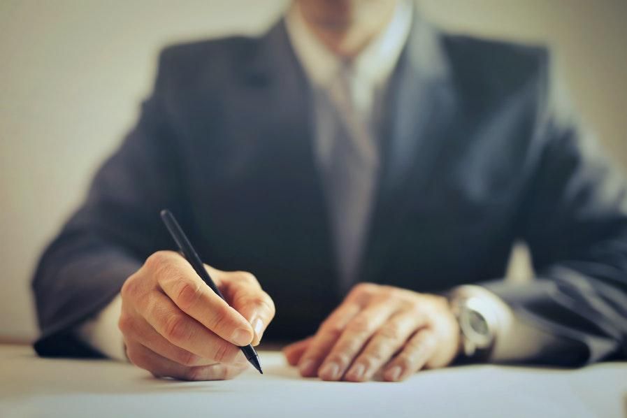 a person in a suit signing a paper