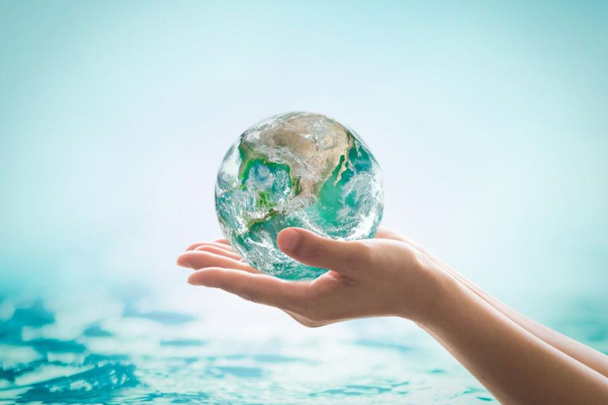 a person's hands holding globe above water