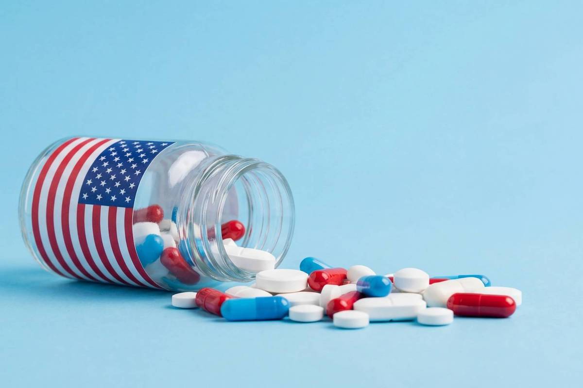 A pill bottle with US flag and coloured pills.