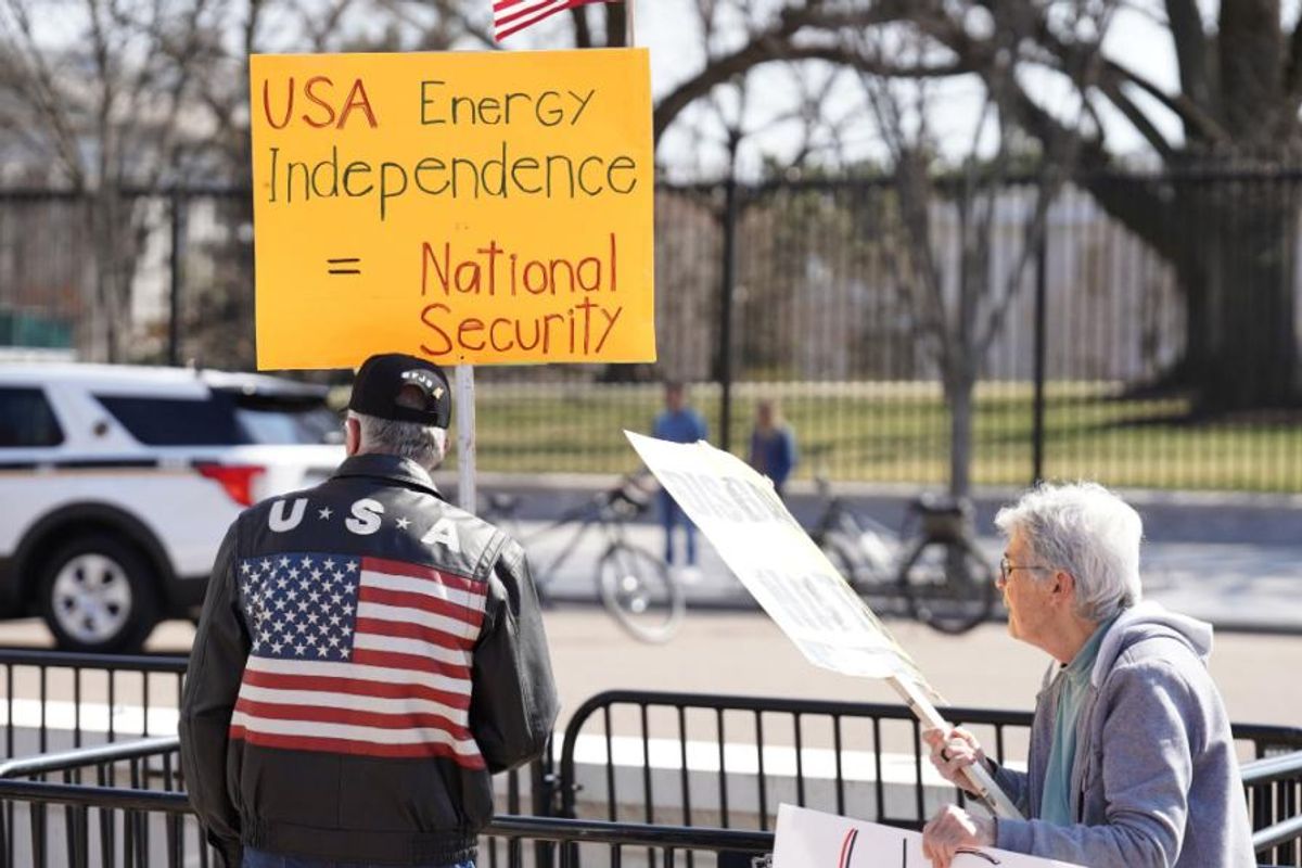a protester holds a sign reading, "USA energy independence = national security"