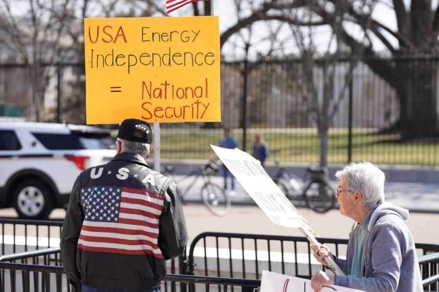 a protester holds a sign reading, "USA energy independence = national security" 