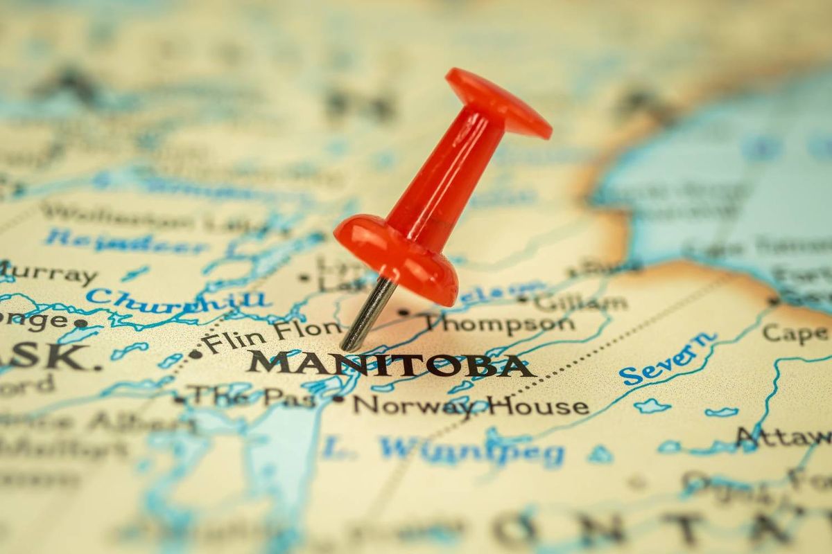 A red pushpin is placed over Manitoba on a detailed map with surrounding regions and water bodies.