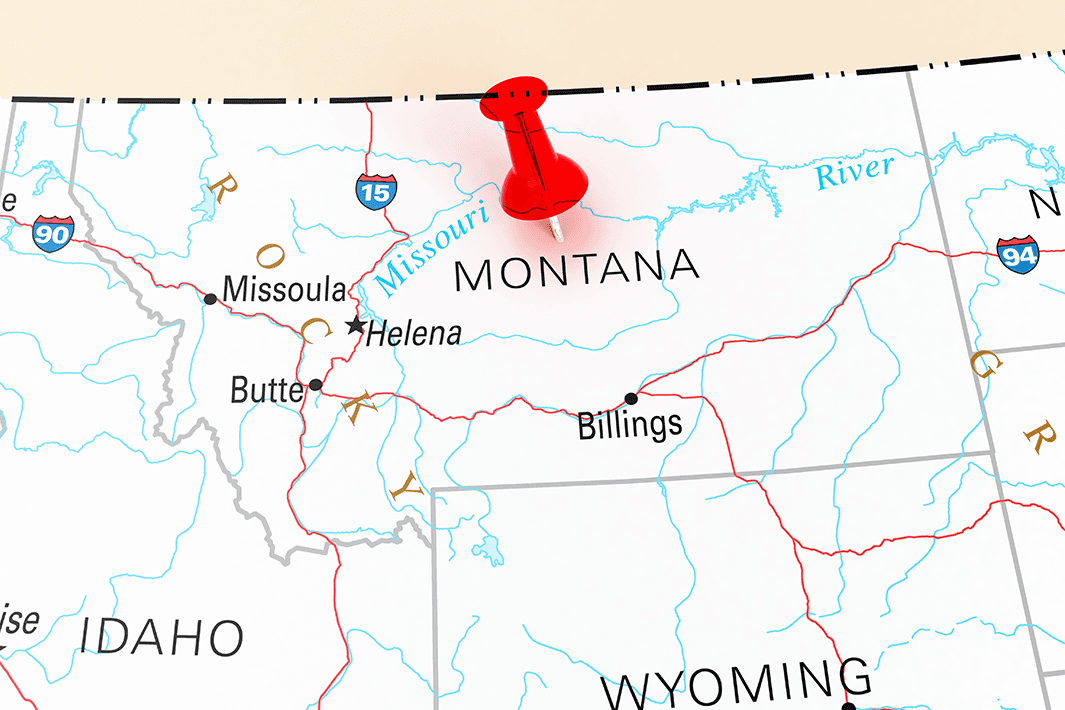 A red pushpin is placed over Montana on a map showing cities and highways.