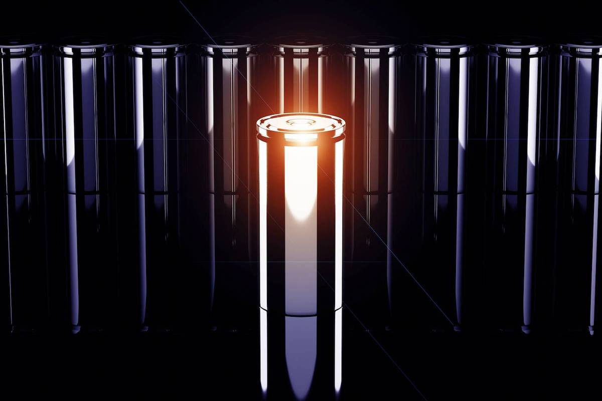 A row of cylindrical batteries with one glowing brightly in orange light against a dark background.
