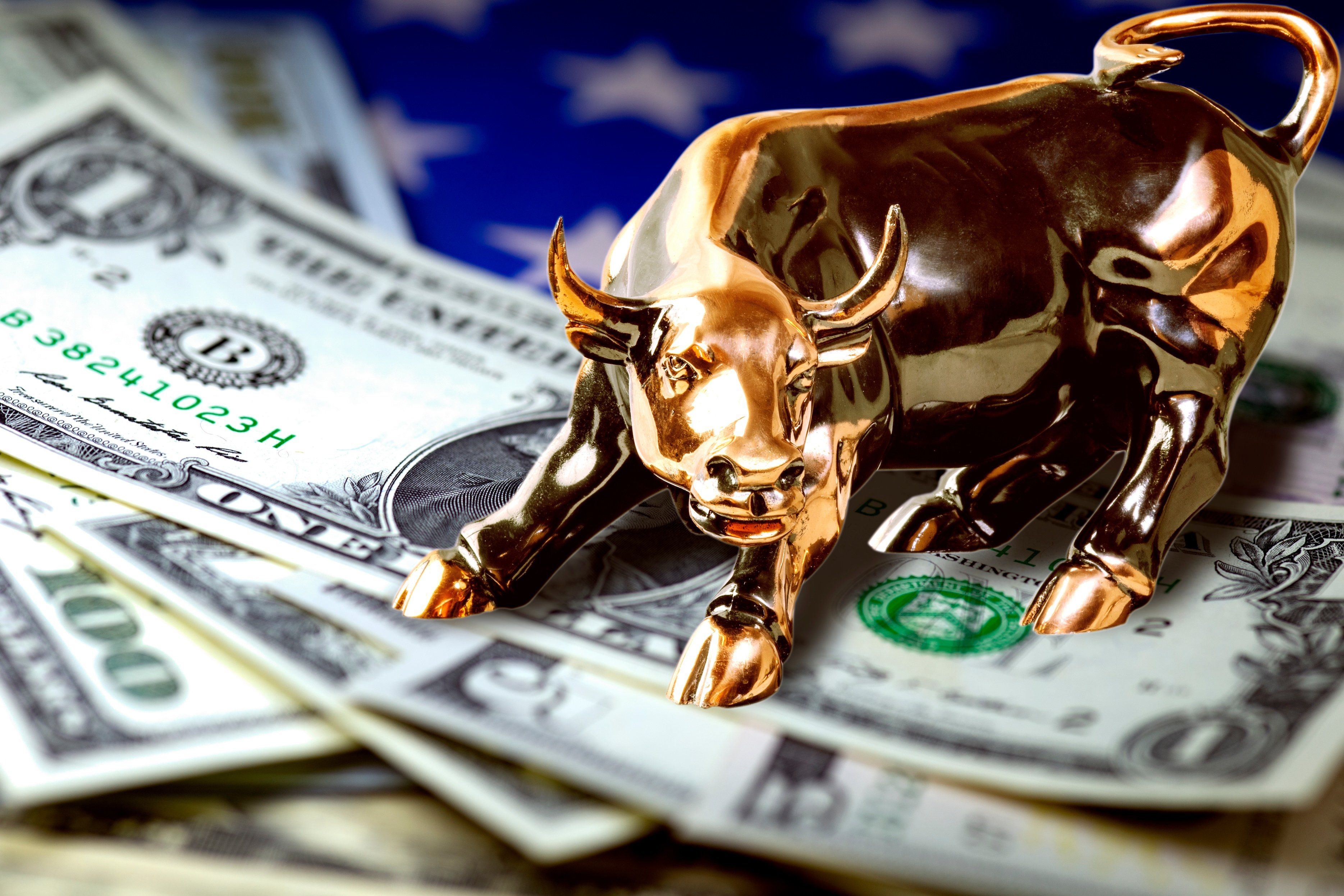 A small golden bull statue on top of US money. 