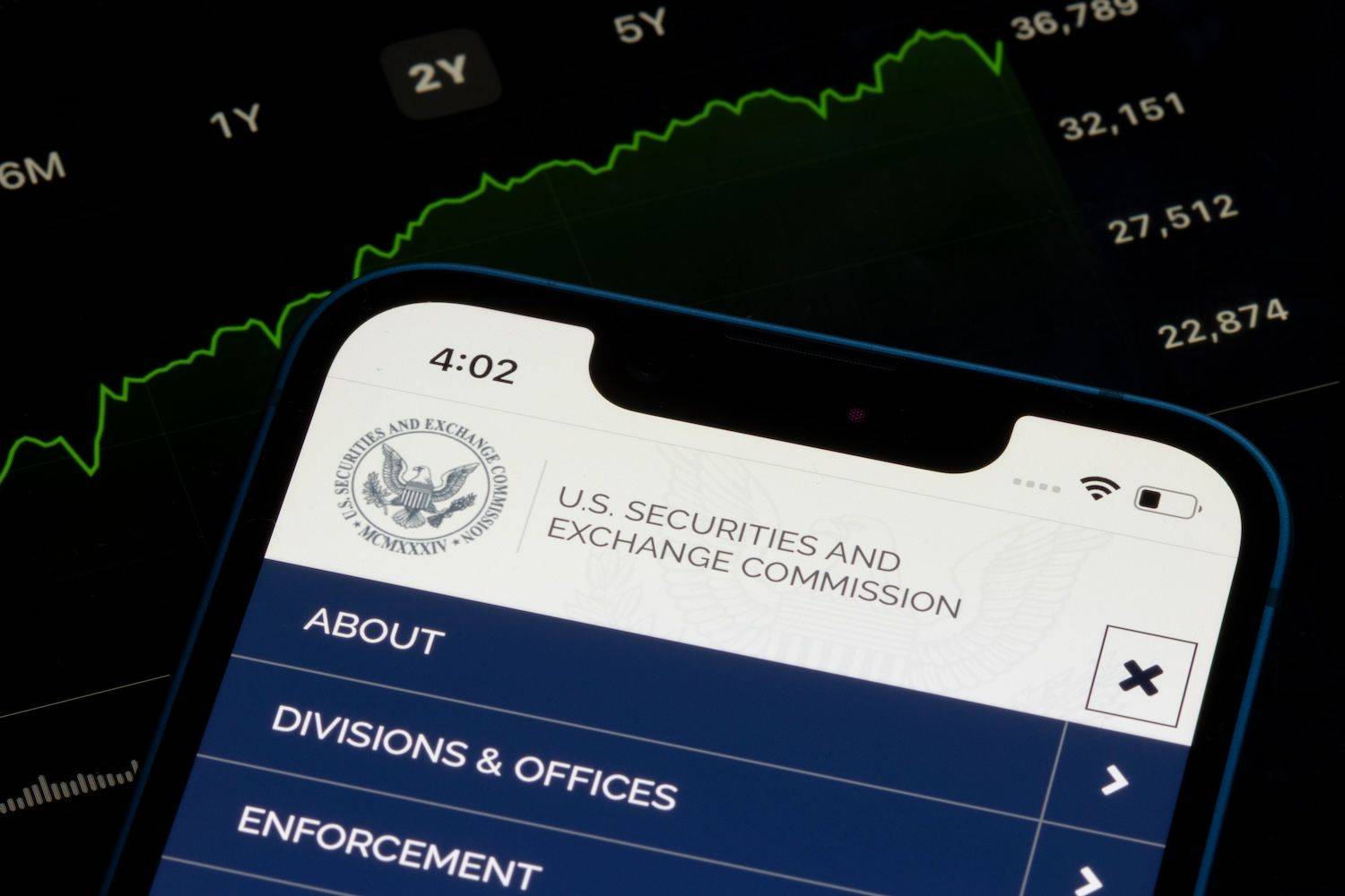 A smartphone displays U.S. Securities and Exchange Commission webpage over a background of a rising stock market graph.