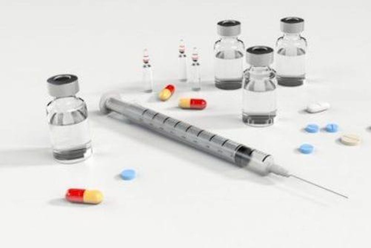 a syringe, vials and pills on a white surface