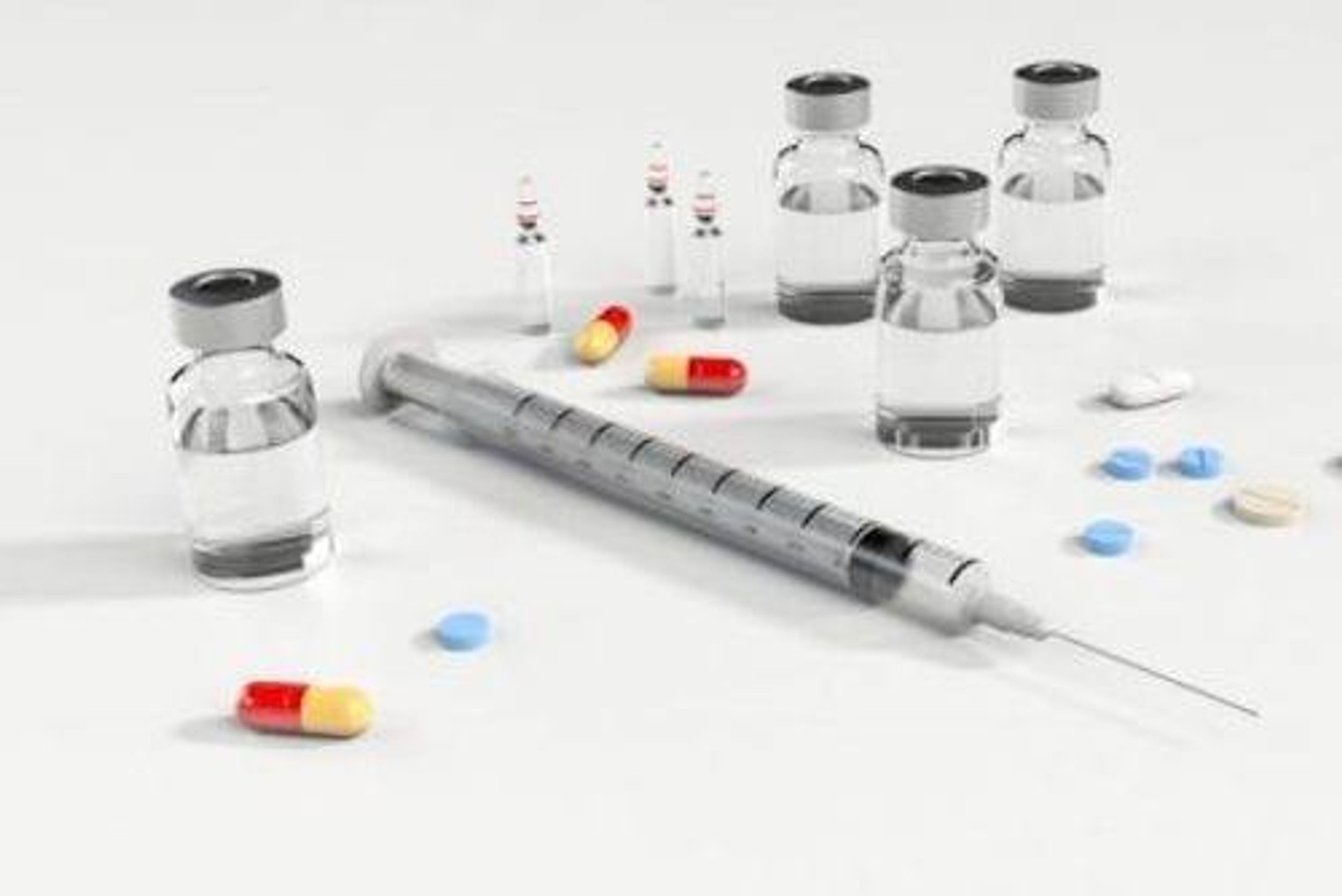 a syringe, vials and pills on a white surface