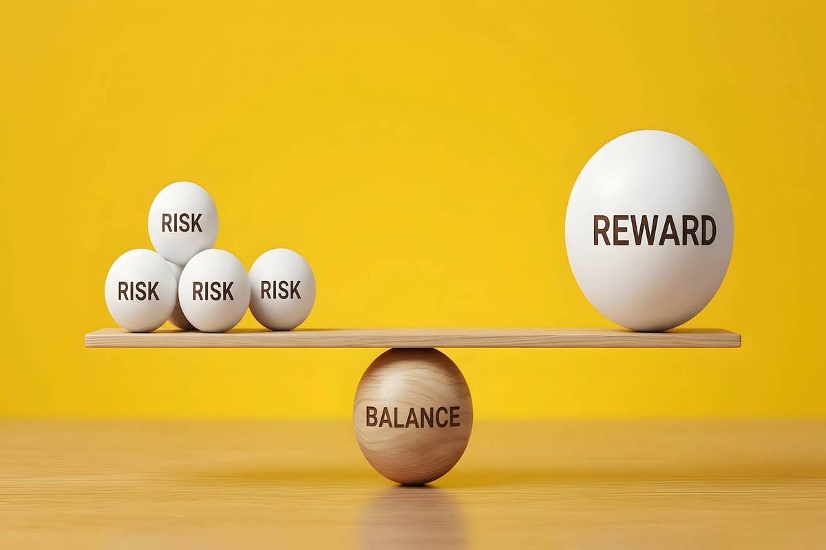 A wooden plank balances on a cylinder labeled "BALANCE" with balls marked "RISK" and "REWARD" against a yellow background.
