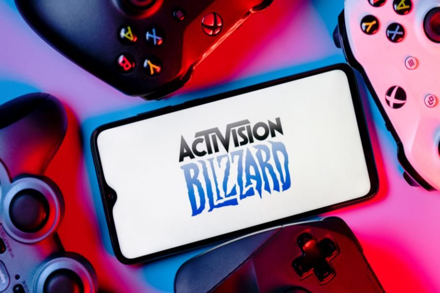 activision blizzard logo on a phone with gaming controllers surrounding it