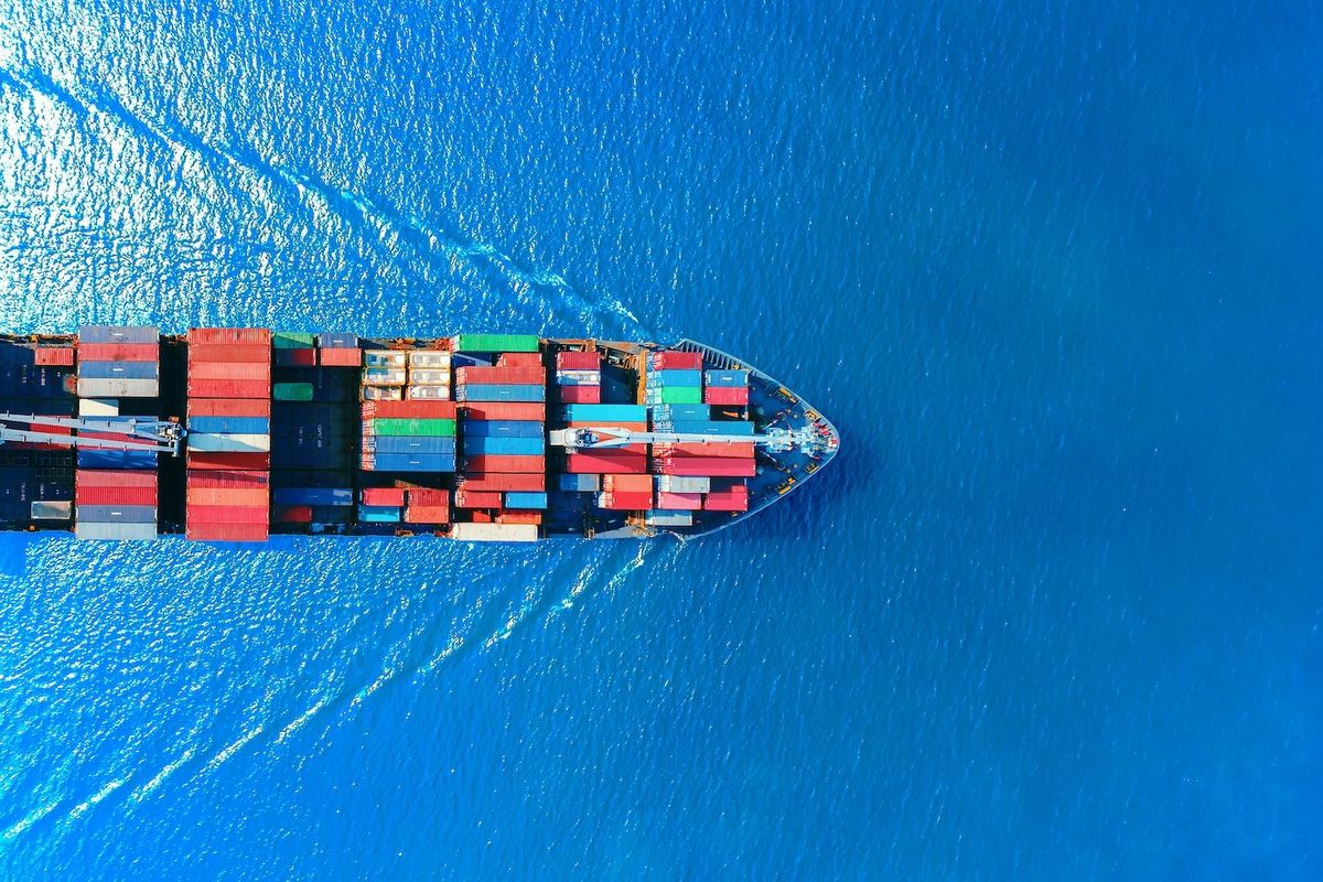 Aerial view of a cargo ship with colorful containers in vibrant blue ocean.