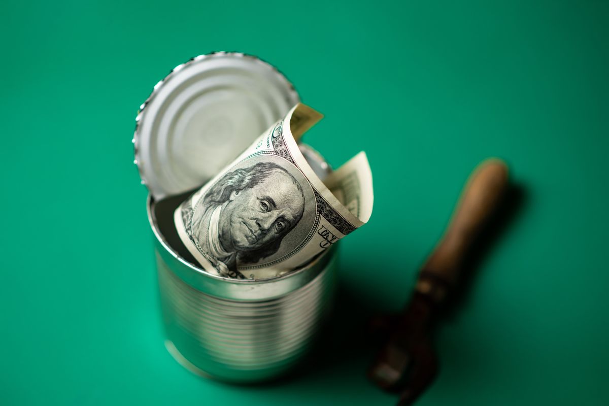 An open tin can with US money inside. 