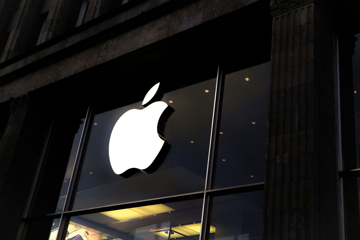 Apple logo on a glass storefront, dim lighting inside the building.