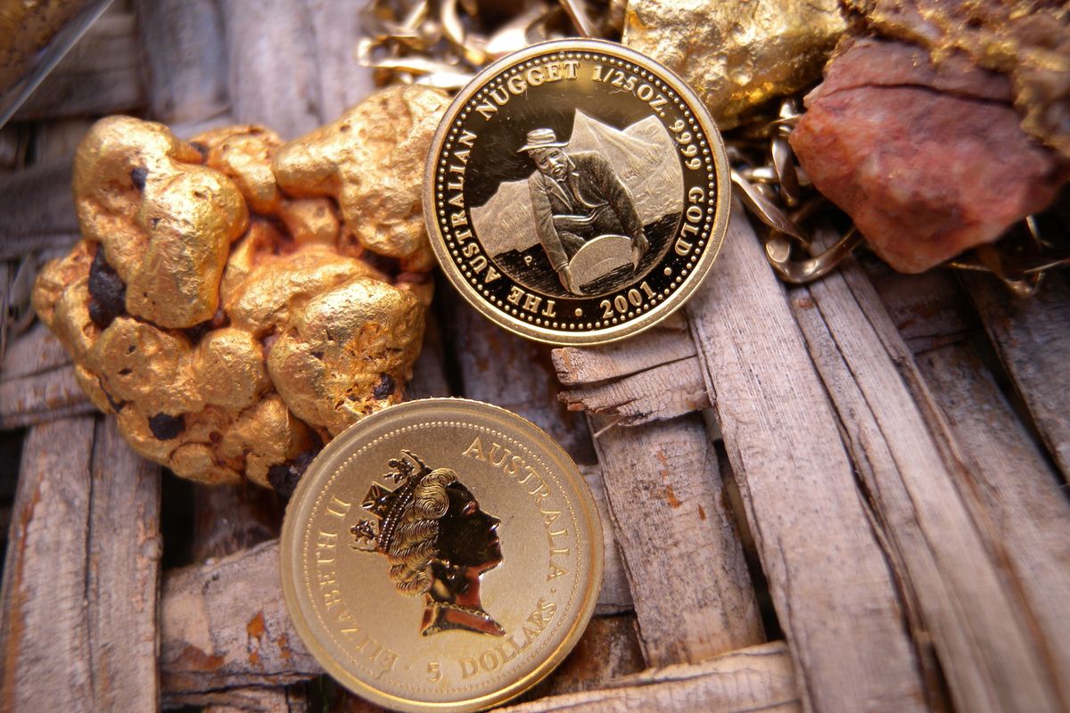 Australian gold nugget coins and gold nuggets on a wooden surface.