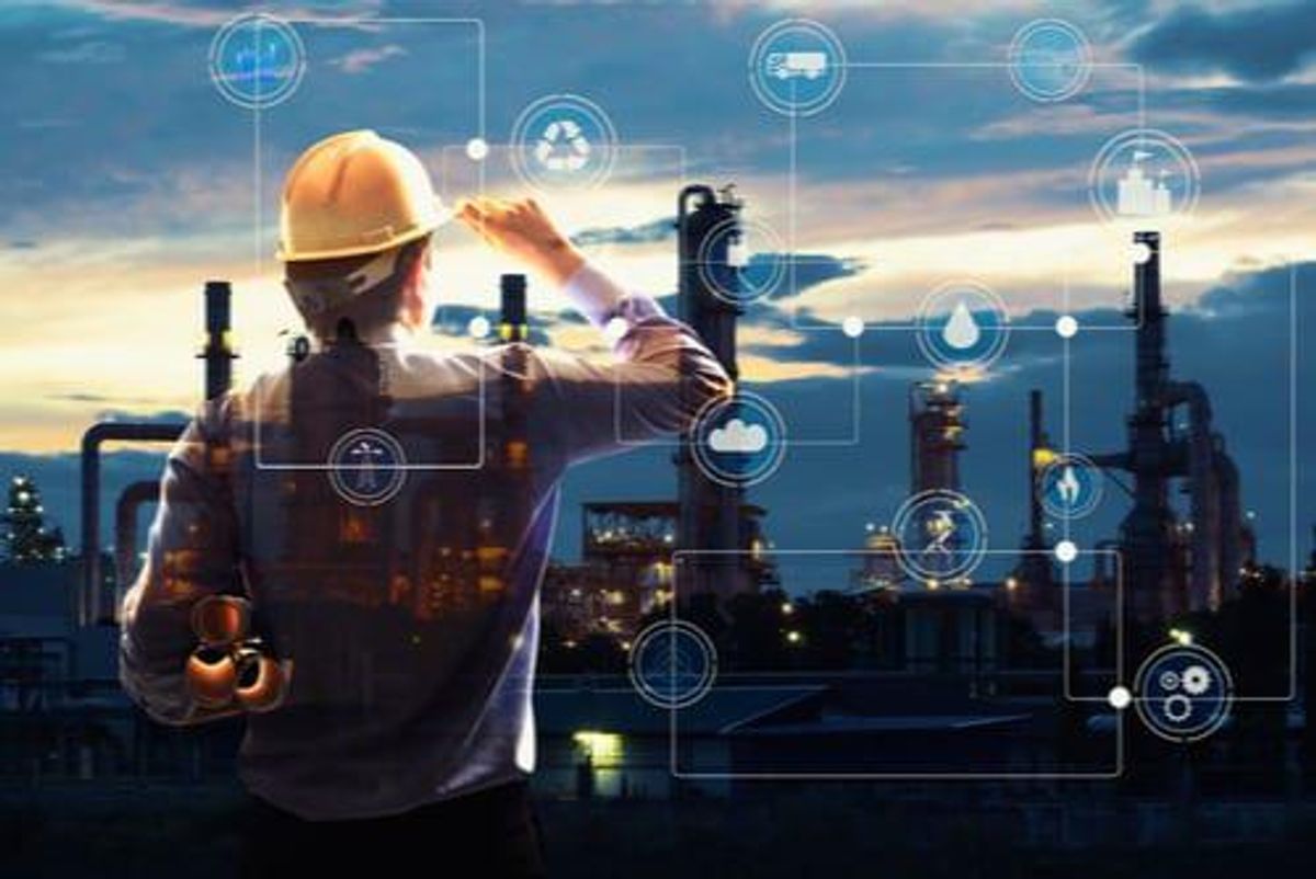 back of man in yellow hard hat looking at oil refinery plant