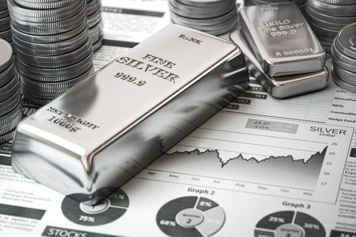 bar of silver and coins on top of a newspaper with three pie charts on it