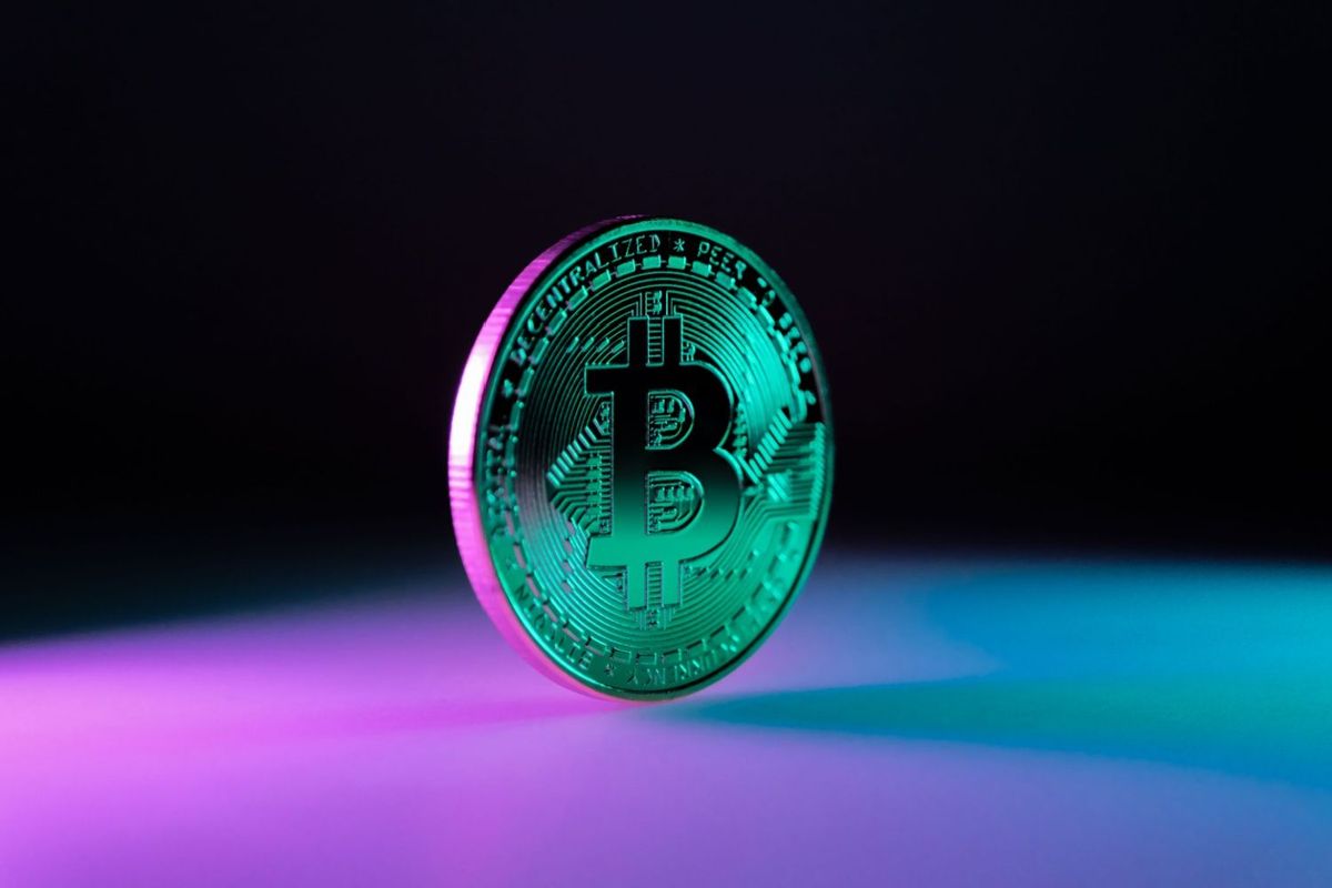 Bitcoin against purple and teal background.