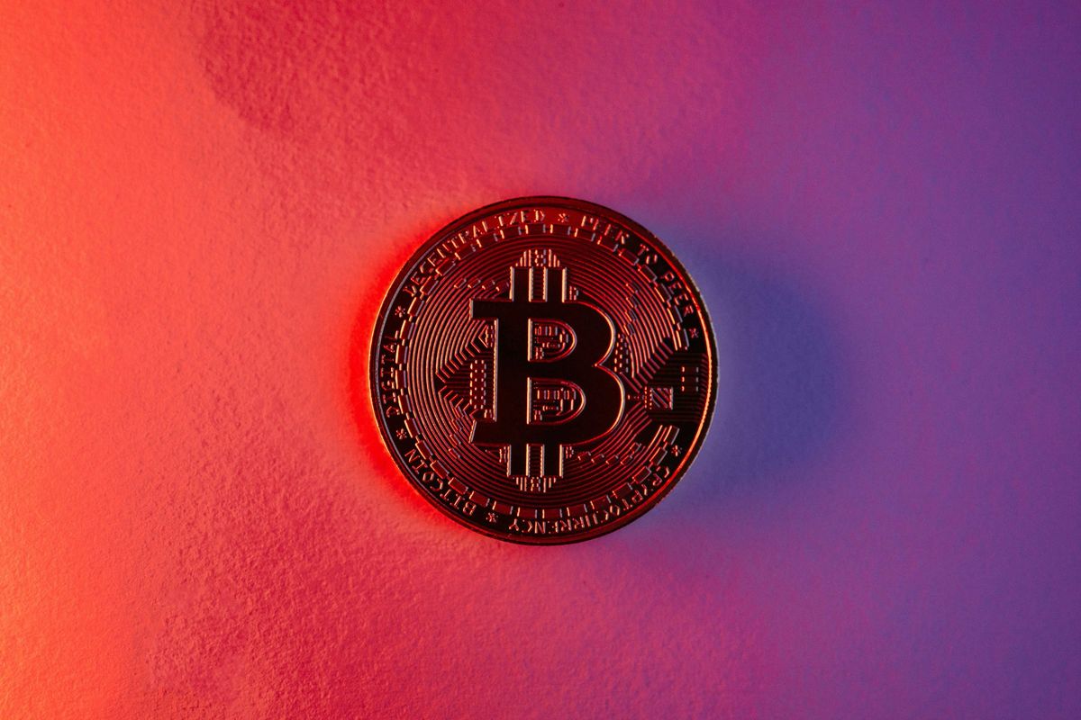 Bitcoin coin on red and purple gradient background.