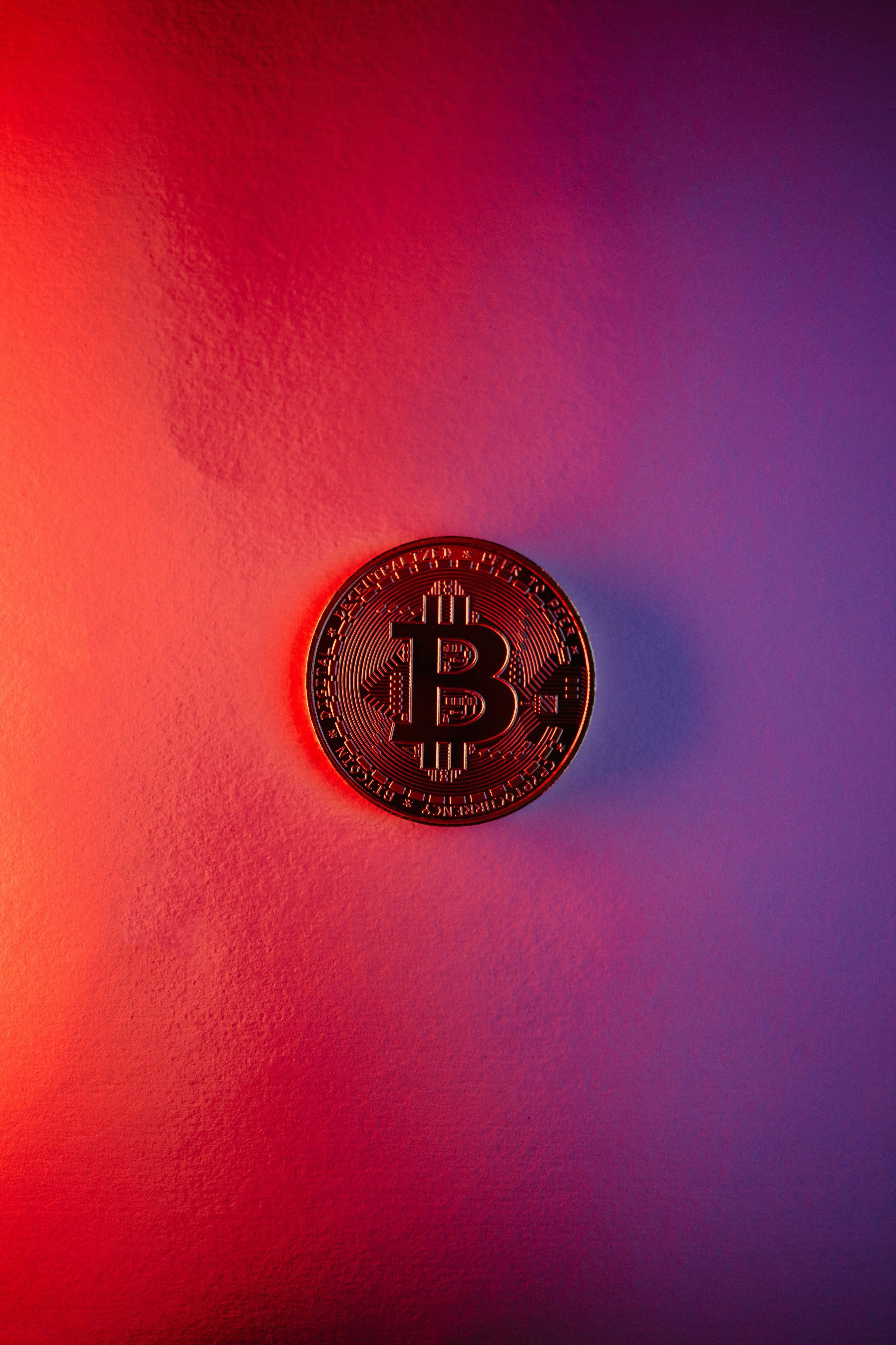 Bitcoin coin on red and purple gradient background.