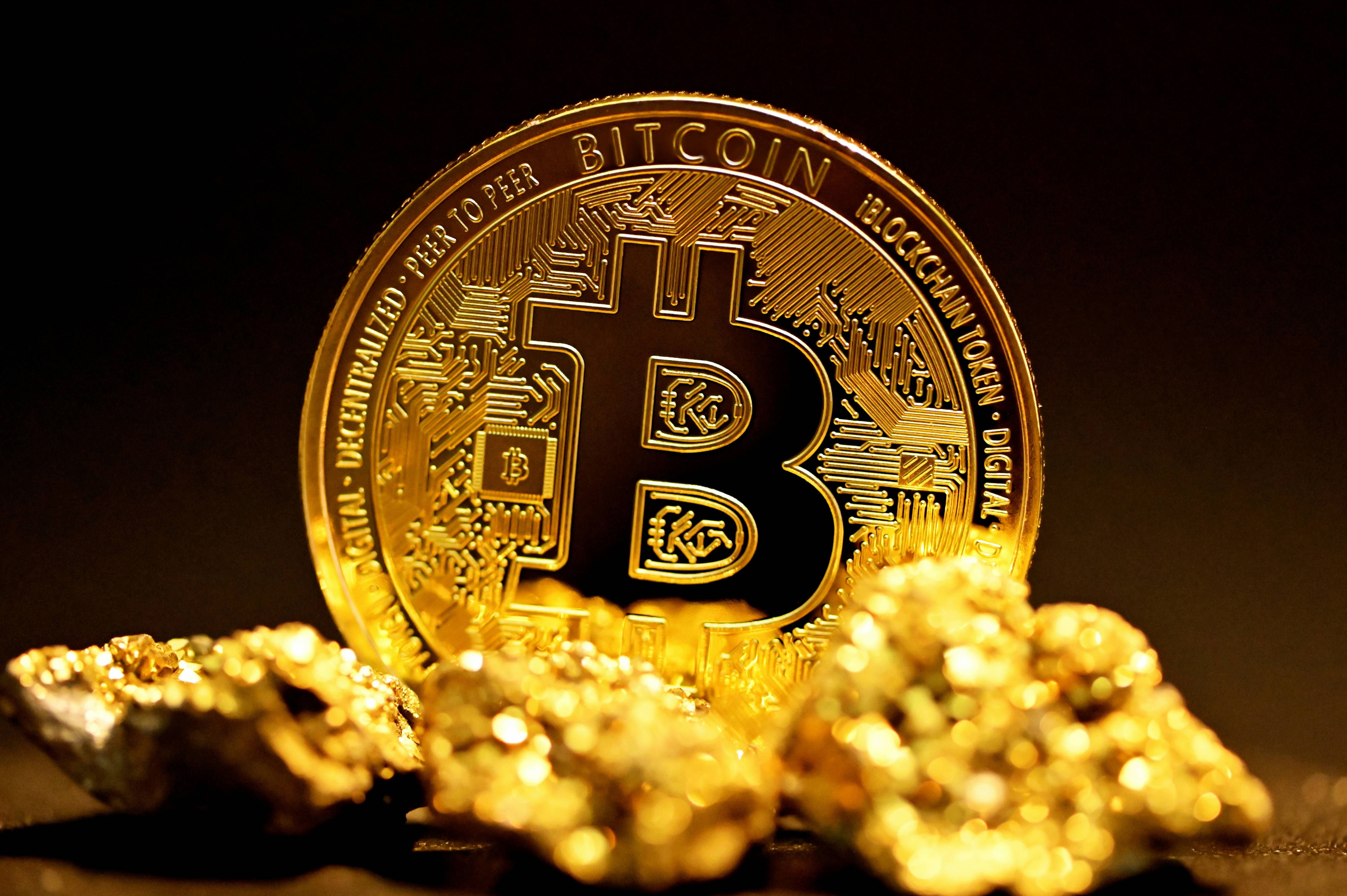 Bitcoin coin surrounded by gold nuggets on a dark background.