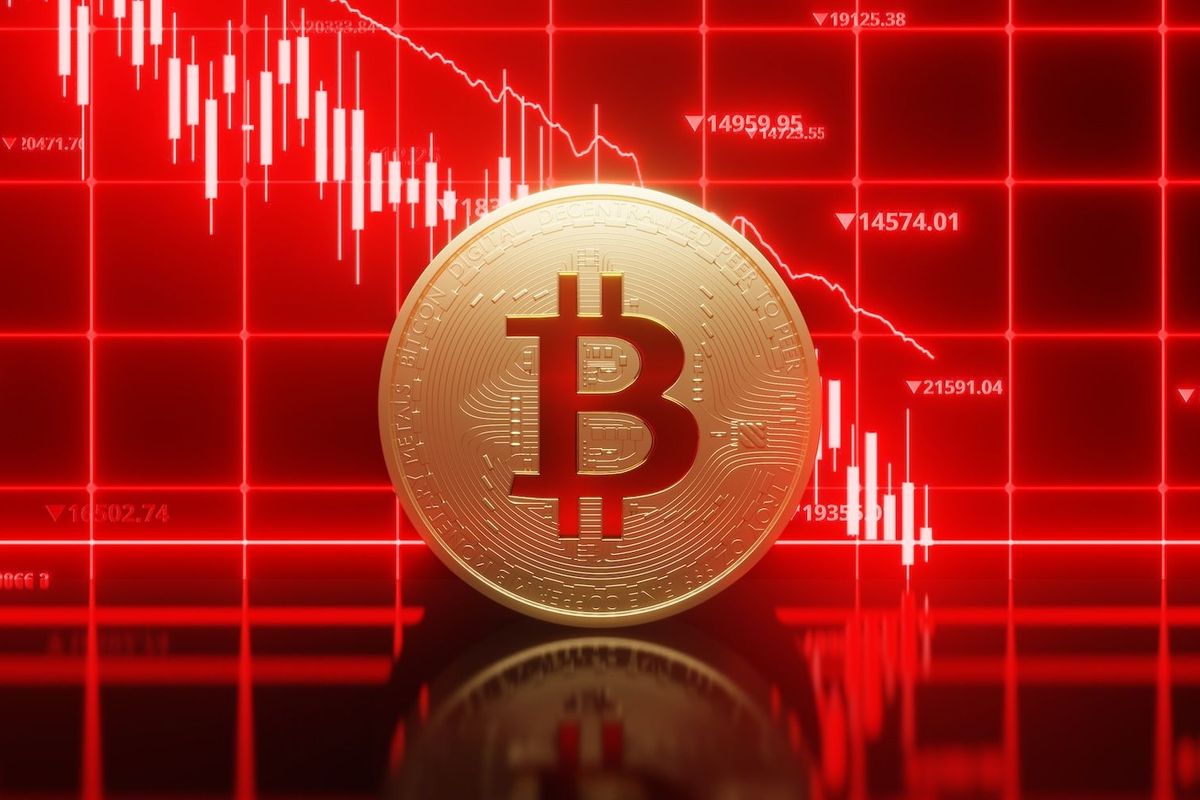 Bitcoin coin with a declining red stock chart in the background.