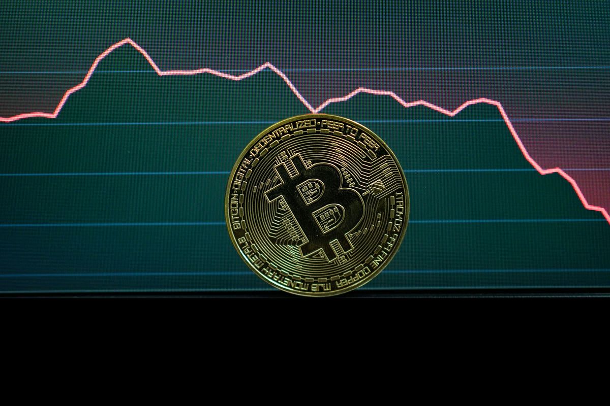 Bitcoin in front of declining stock graph.
