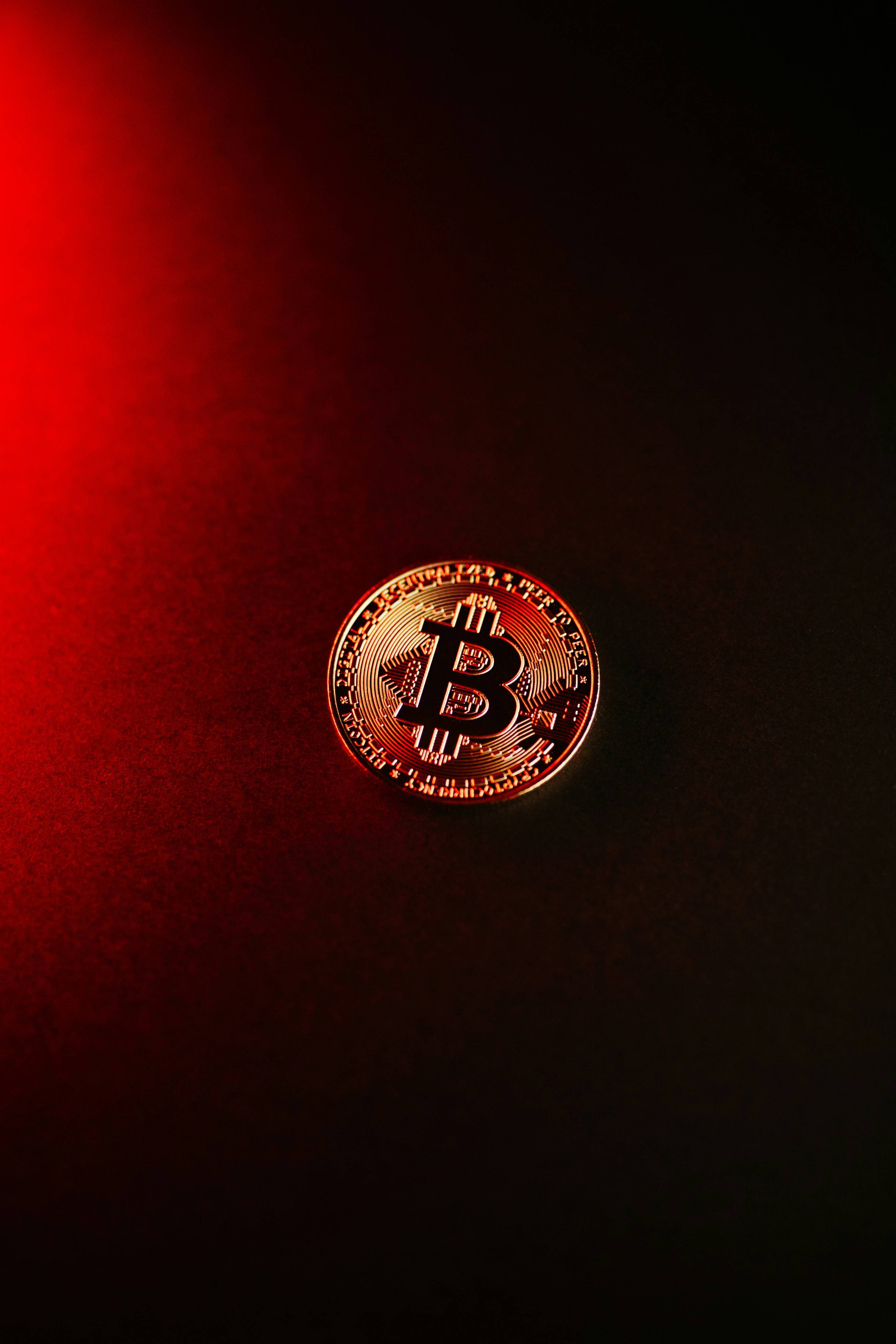 Bitcoin on a dark surface with red lighting.
