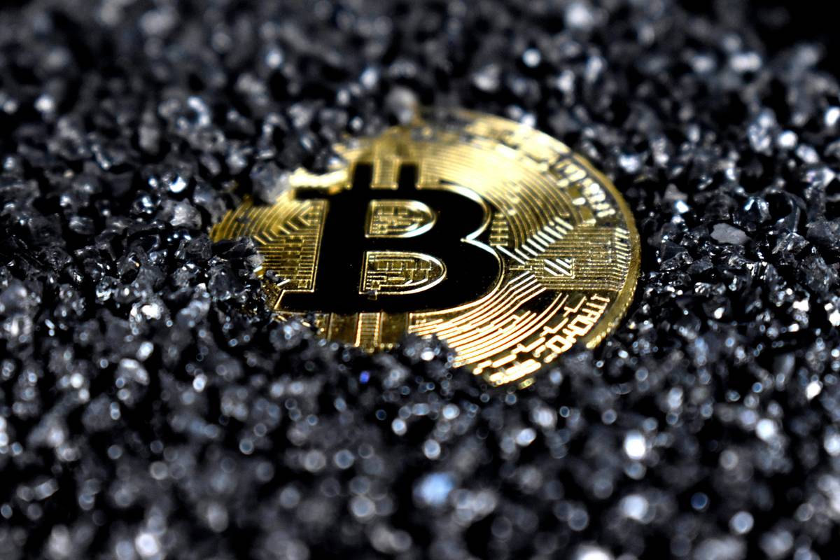 Bitcoin partially covered in black gravel.