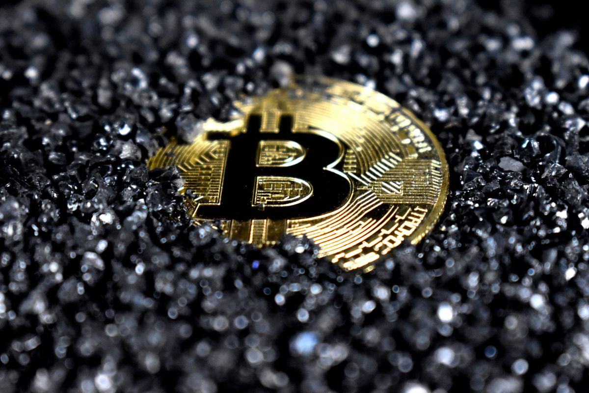 Bitcoin partially covered in black gravel.