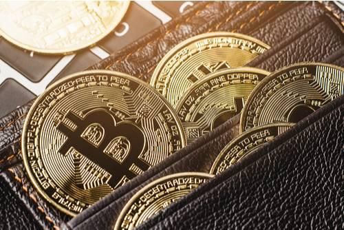 bitcoins in a leather wallet on a calculator