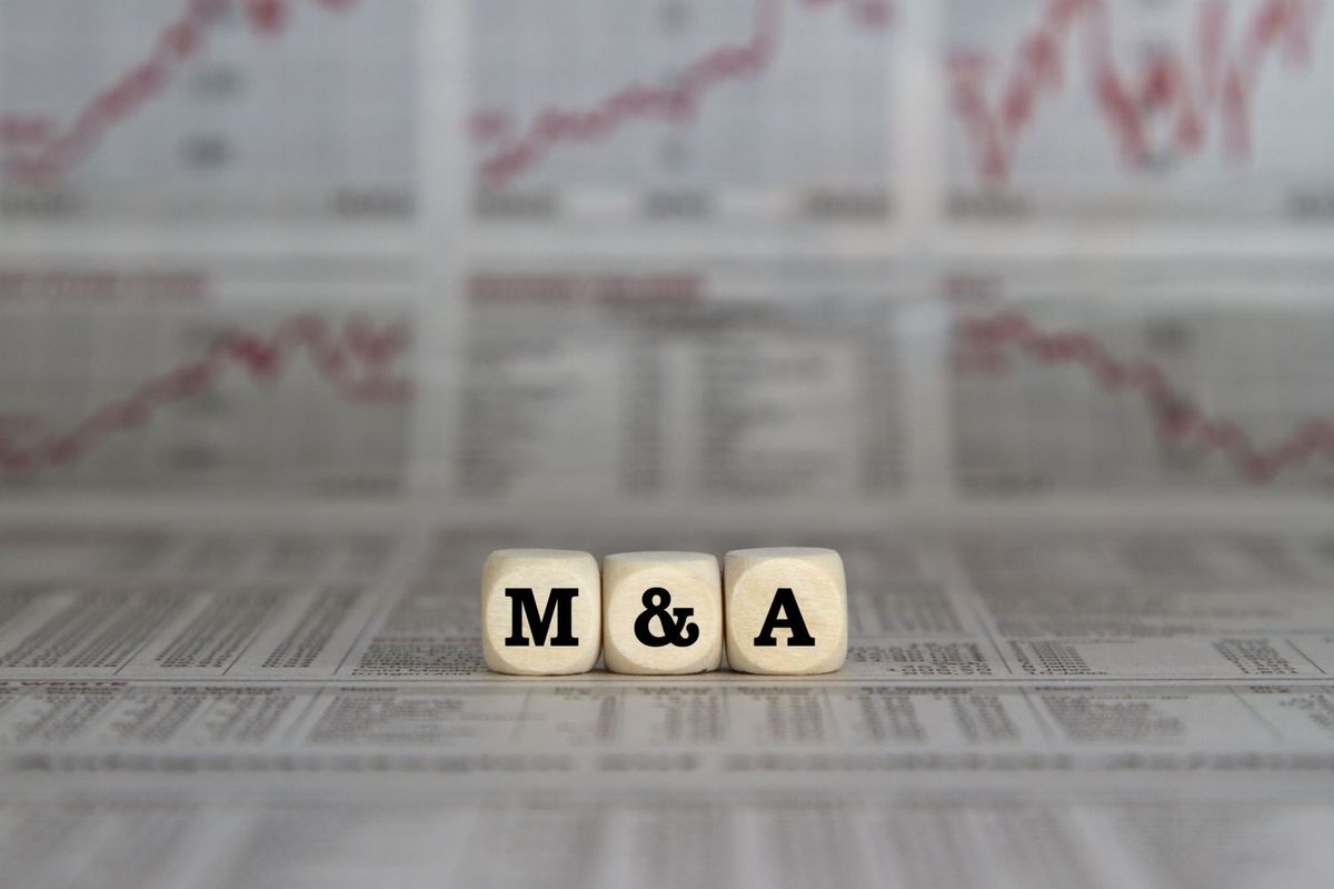 Blocks spelling "M&A" with stock charts in background.