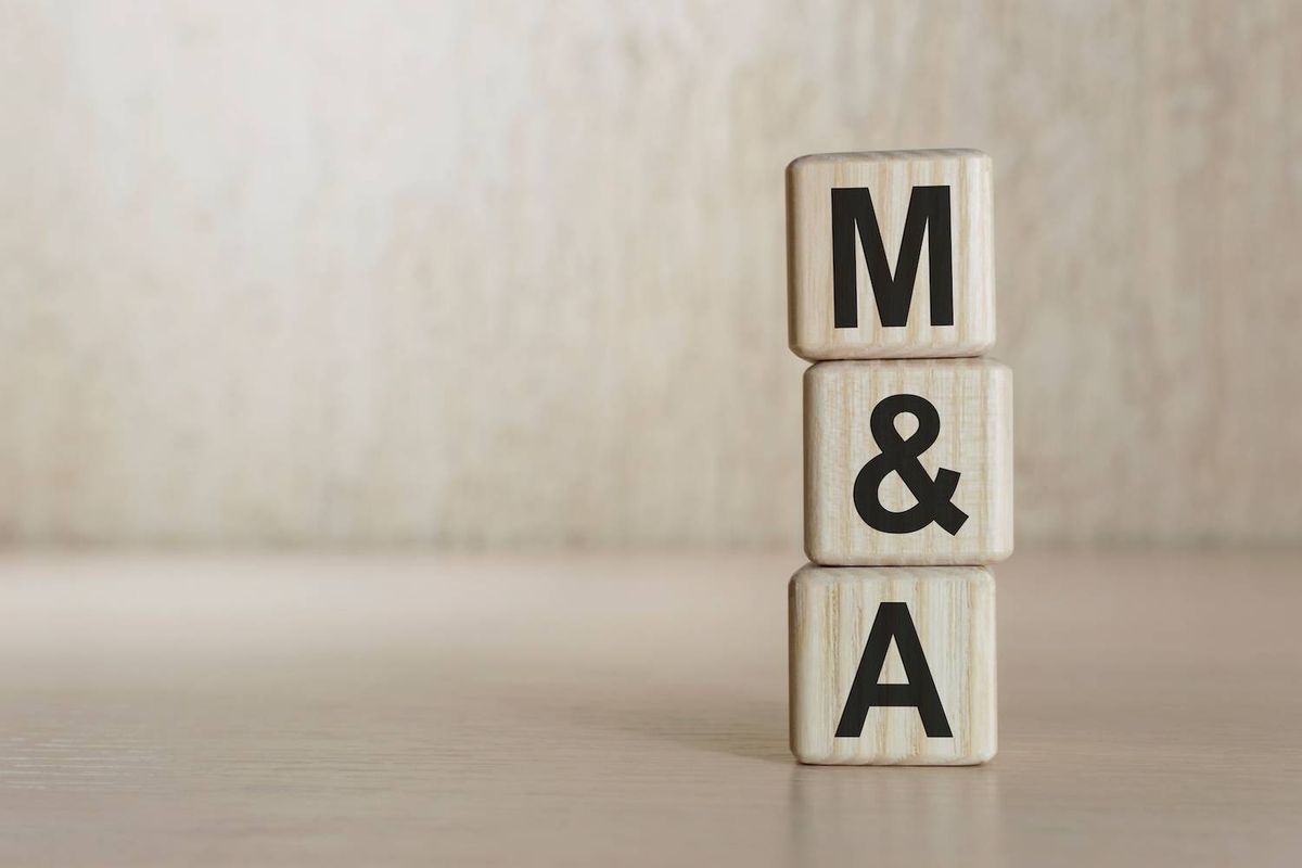 Blocks stacked to form "M&A" on a wooden surface.