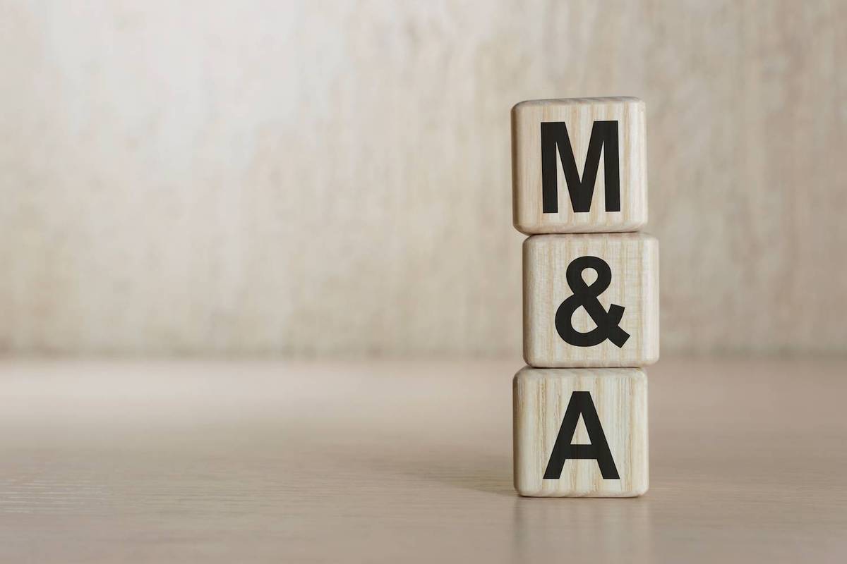 Blocks stacked to form "M&A" on a wooden surface.