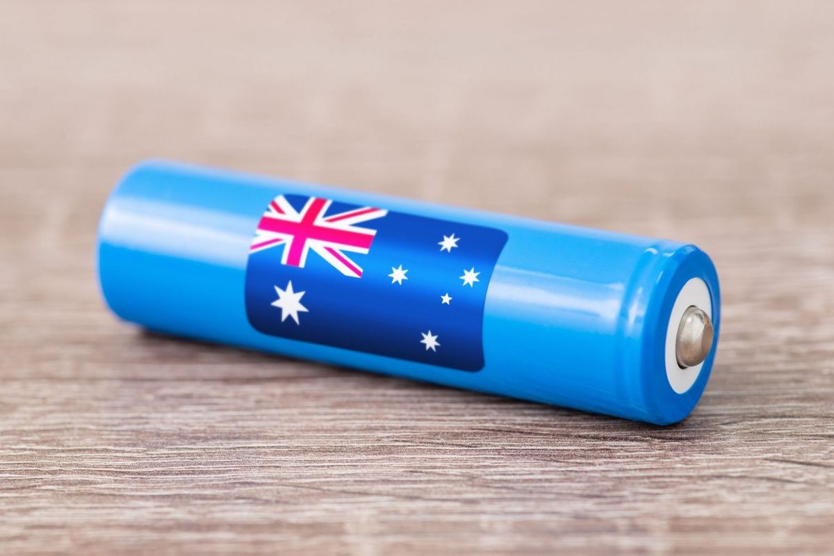 Blue battery with an Australian flag on its side sitting on a light brown wooden surface.