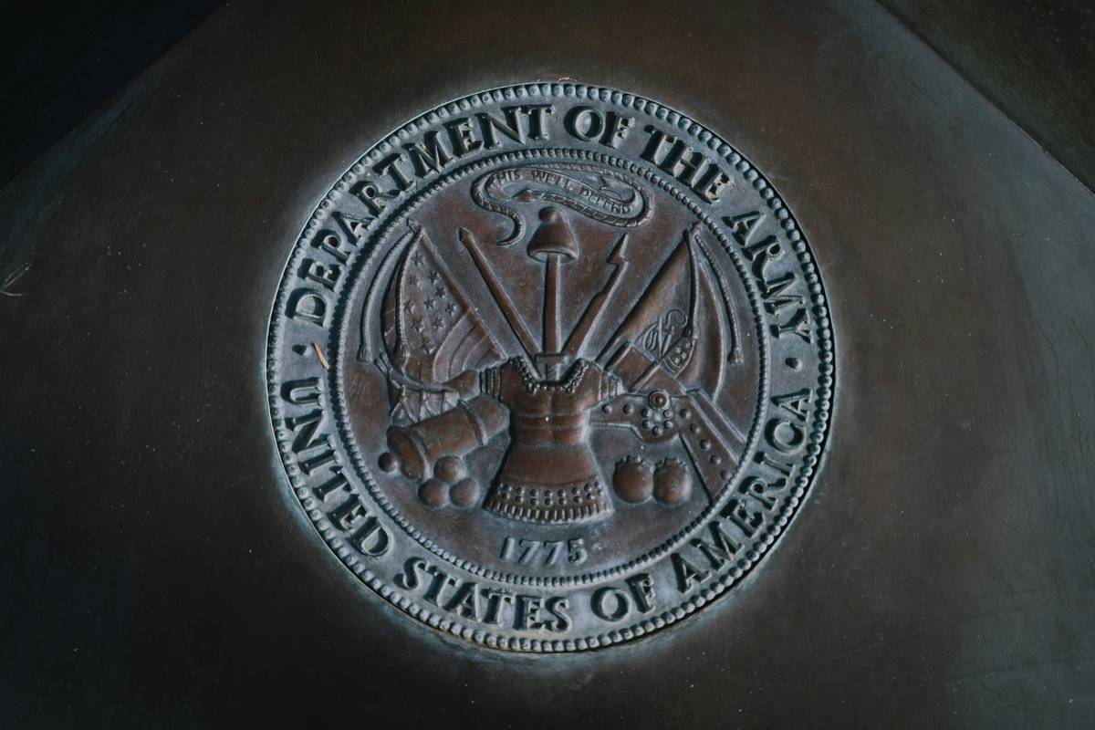 Bronze seal with insignia and weapons, surrounded by text: "Department of the Army, United States of America."