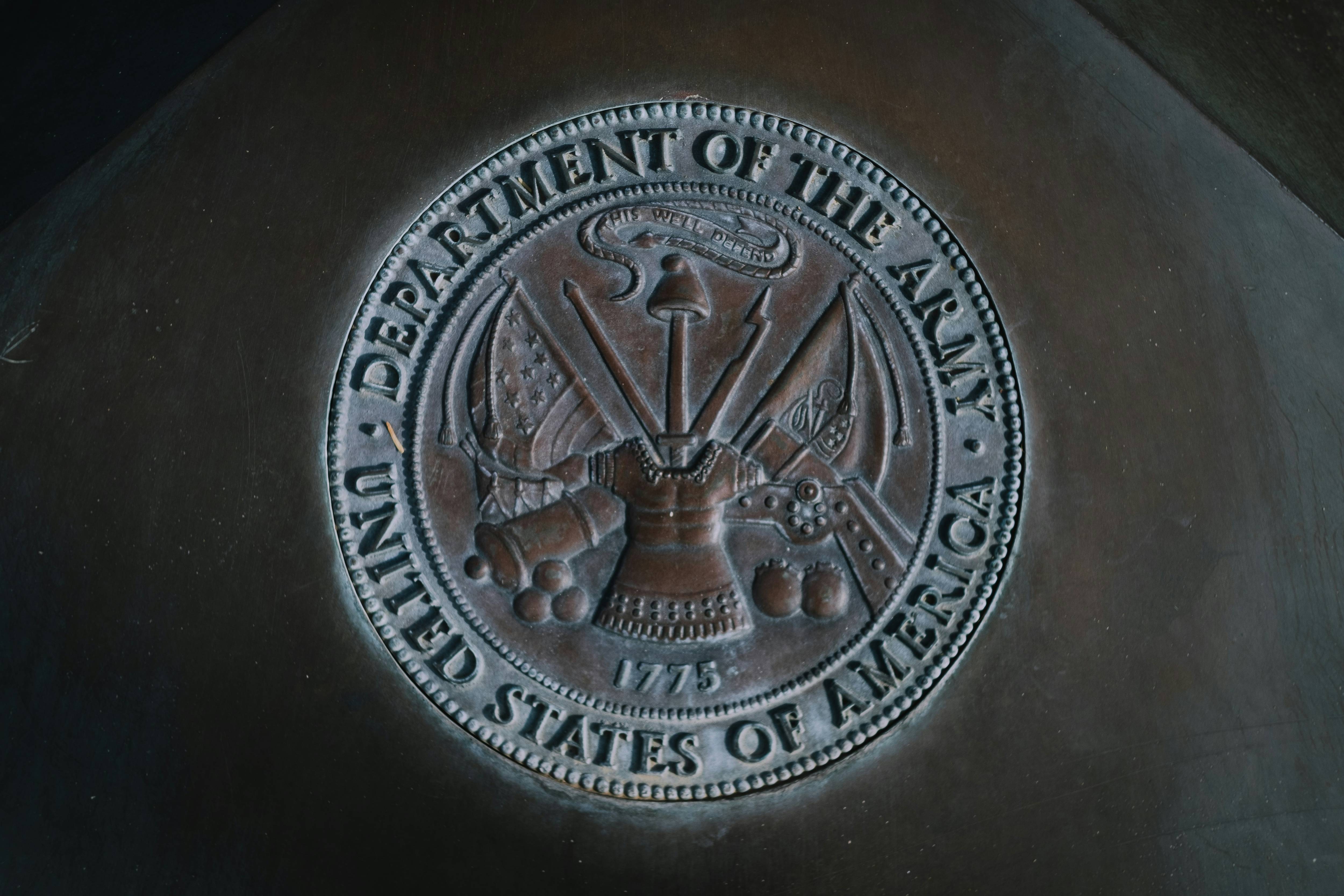Bronze seal with insignia and weapons, surrounded by text: "Department of the Army, United States of America."