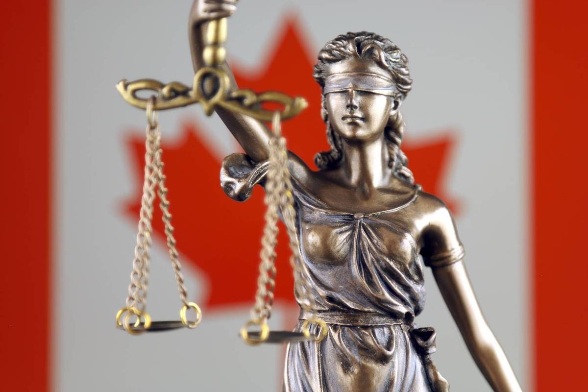 Bronze statue of Lady Justice holding scales, in front of a blurred Canadian flag background with red maple leaf.