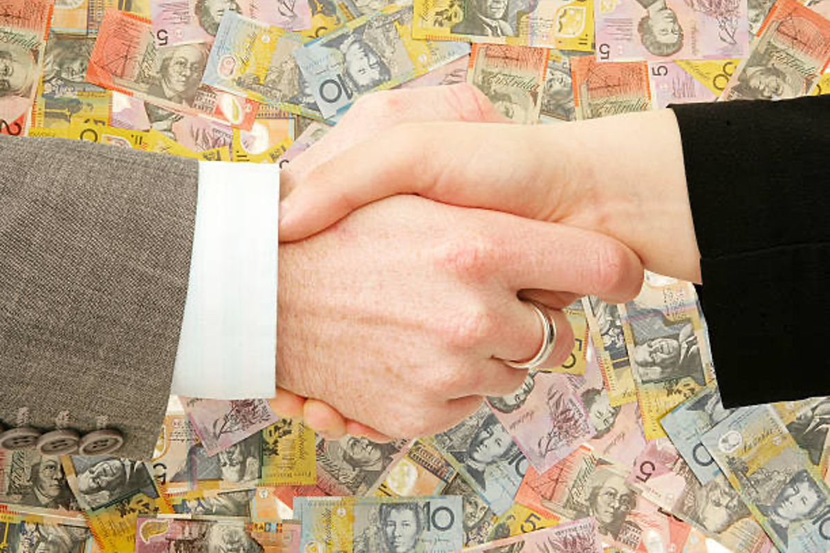 Business handshake with Australian money in background.